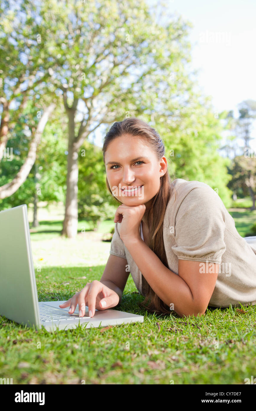 Smiling woman with her laptop while lying on the lawn Stock Photo - Alamy
