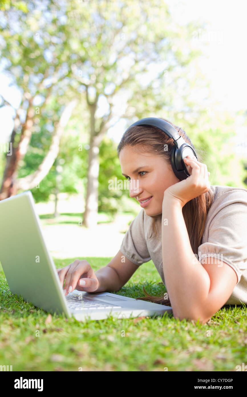 Woman with headphones and a laptop lying on the lawn Stock Photo - Alamy