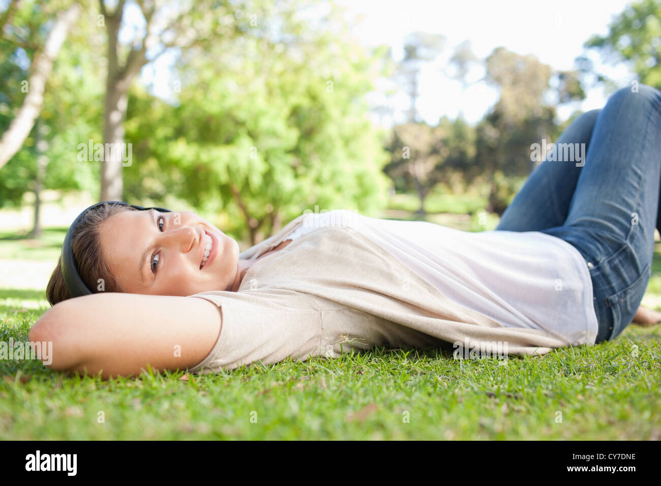 Woman lying on the grass while listening to music Stock Photo - Alamy