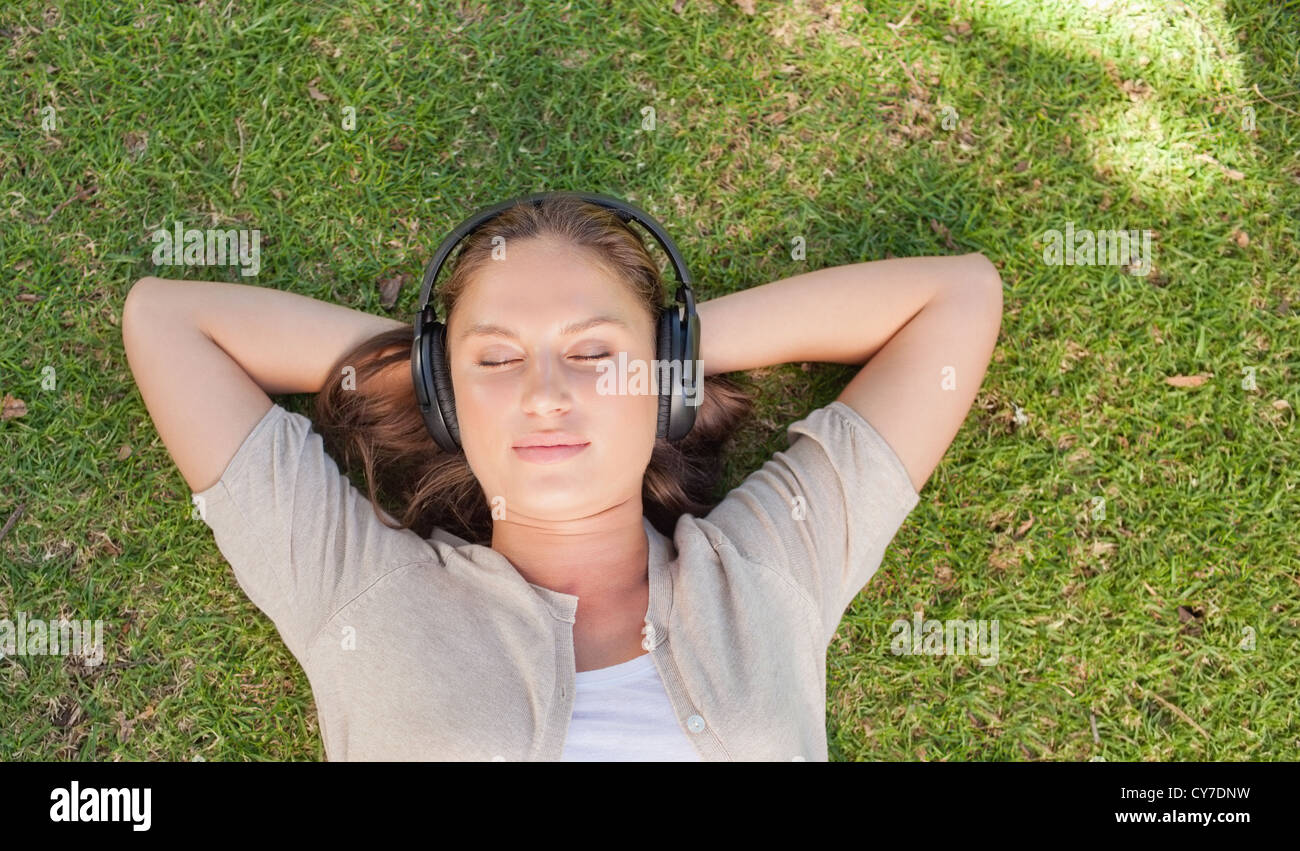 Relaxed woman listening to music while lying on the lawn Stock Photo ...