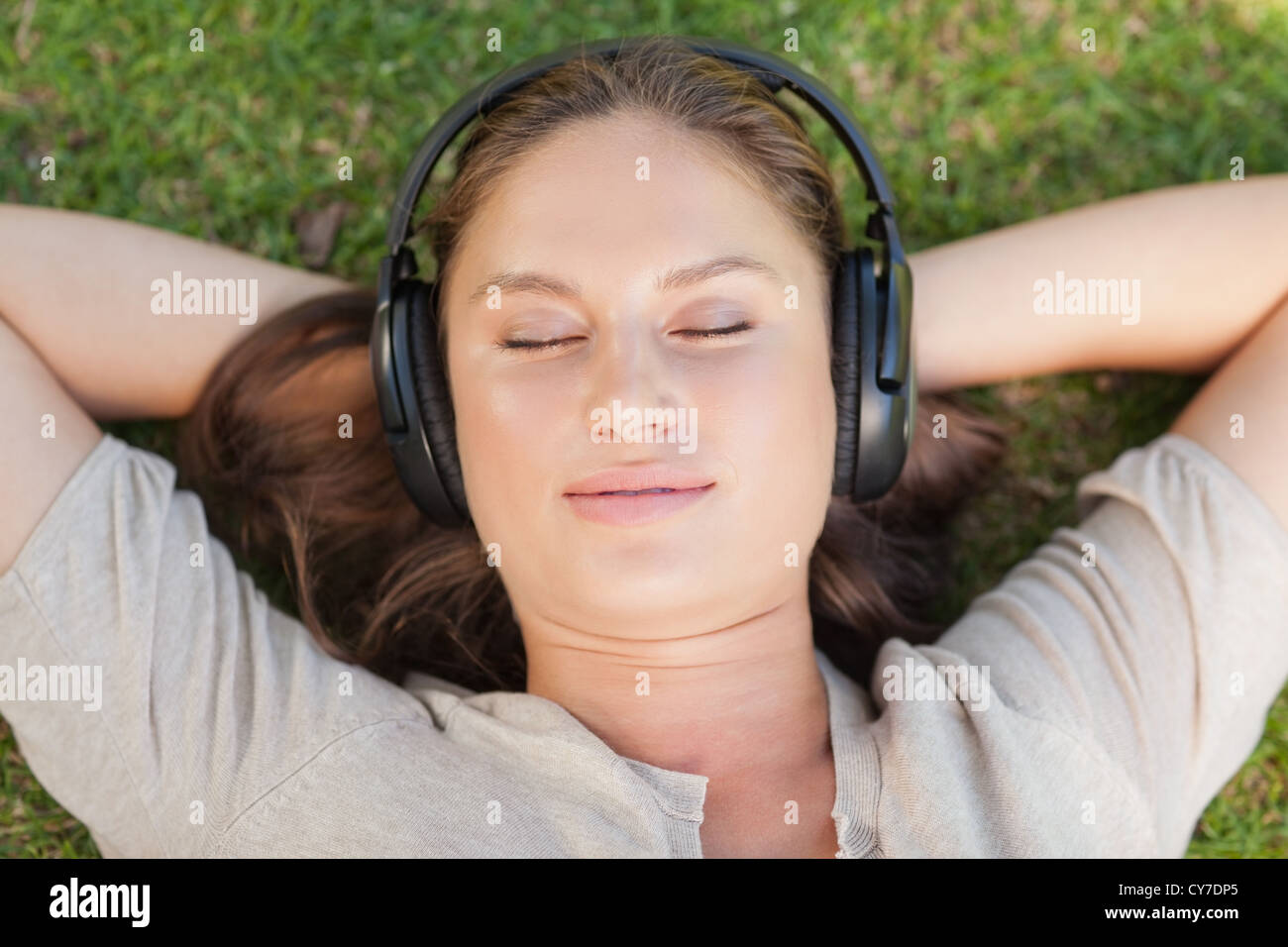 Relaxed woman lying on the lawn while listening to music Stock Photo ...