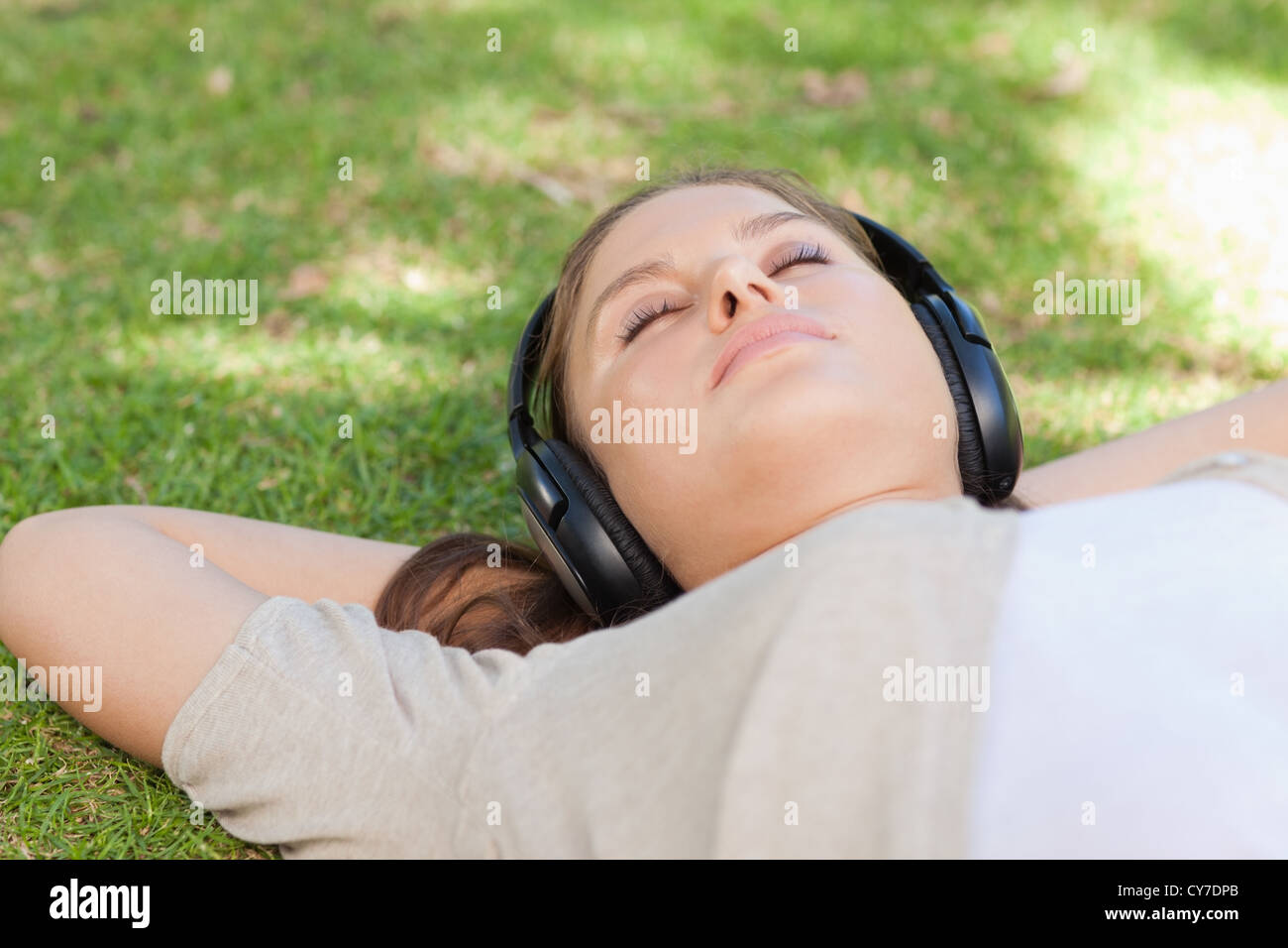 Relaxed woman lying on the lawn enjoying music Stock Photo - Alamy