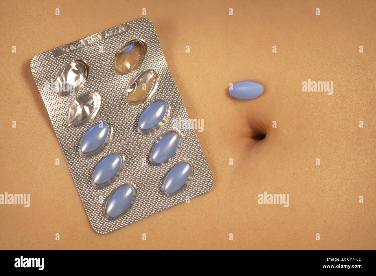Navel of a young healthy woman with blue pills. Stock Photo