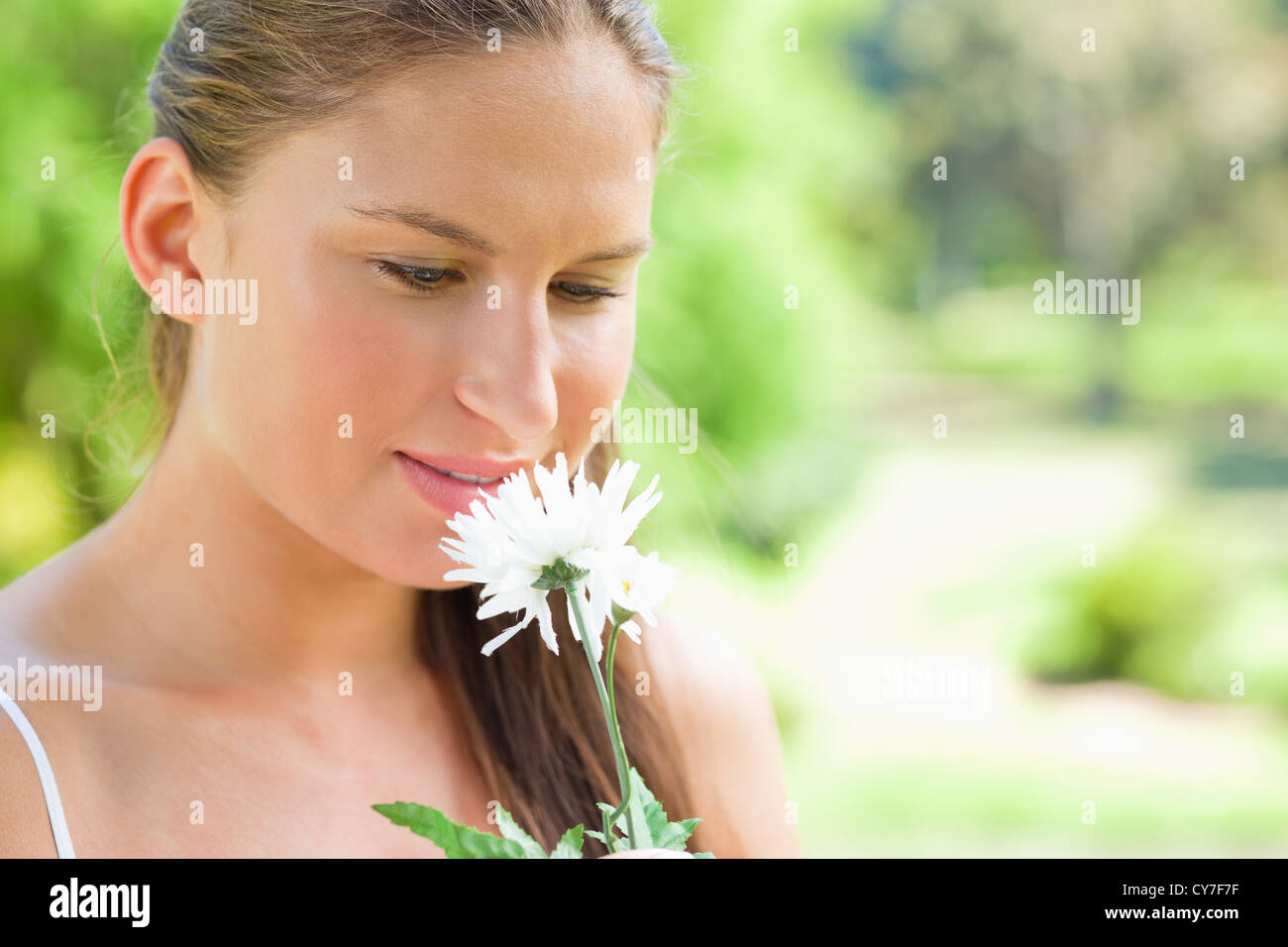 Woman smelling on a white flower in the park Stock Photo - Alamy