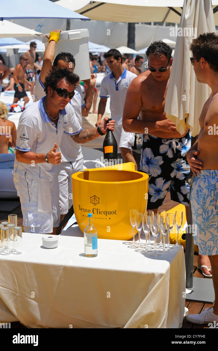 Waiter at beach club party putting bottle of Vueve Cliquot champagne into  large ice bucket Stock Photo - Alamy
