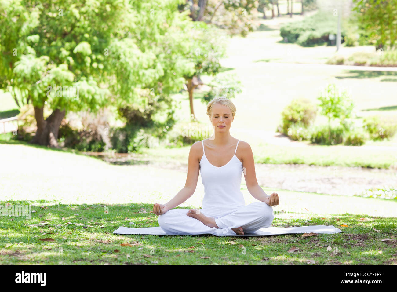 Woman sitting in a yoga position on the lawn Stock Photo - Alamy