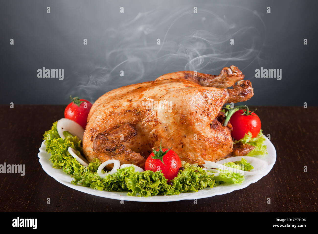 Delicious roast chicken with red tomatoes and green salad, studio shot