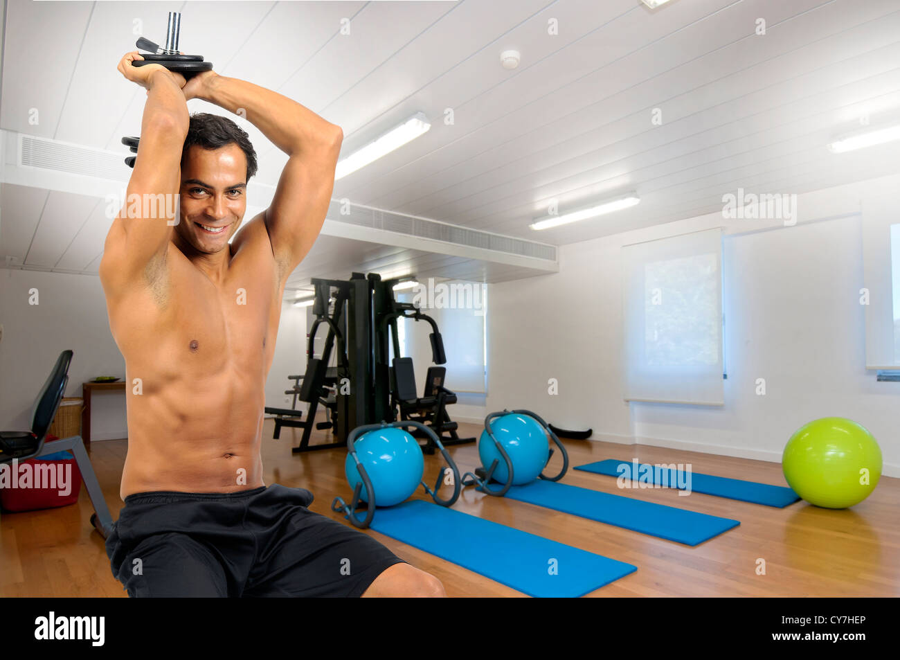 Young fitness man exercising with dumbbells in the gym Stock Photo