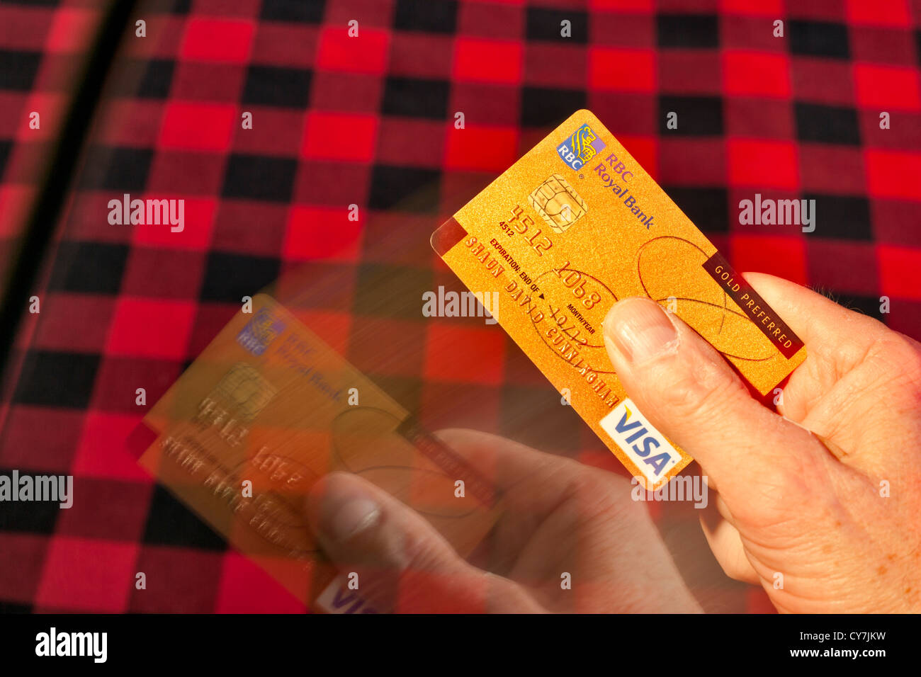 Hand producing motion blurred Visa Gold preferred credit card-Victoria, British Columbia, Canada. Stock Photo