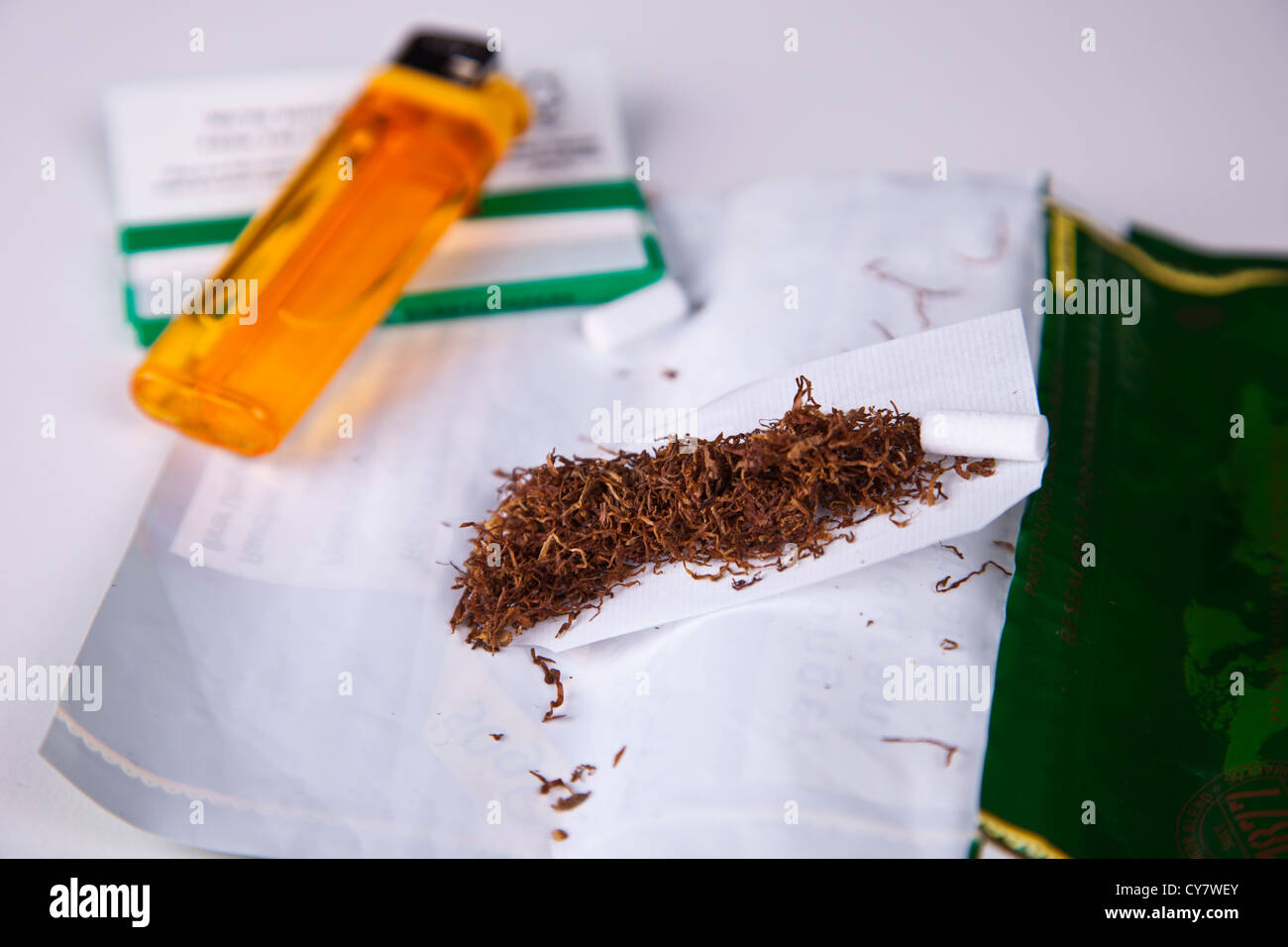 Hand rolling tobacco for making cigarettes. Stock Photo