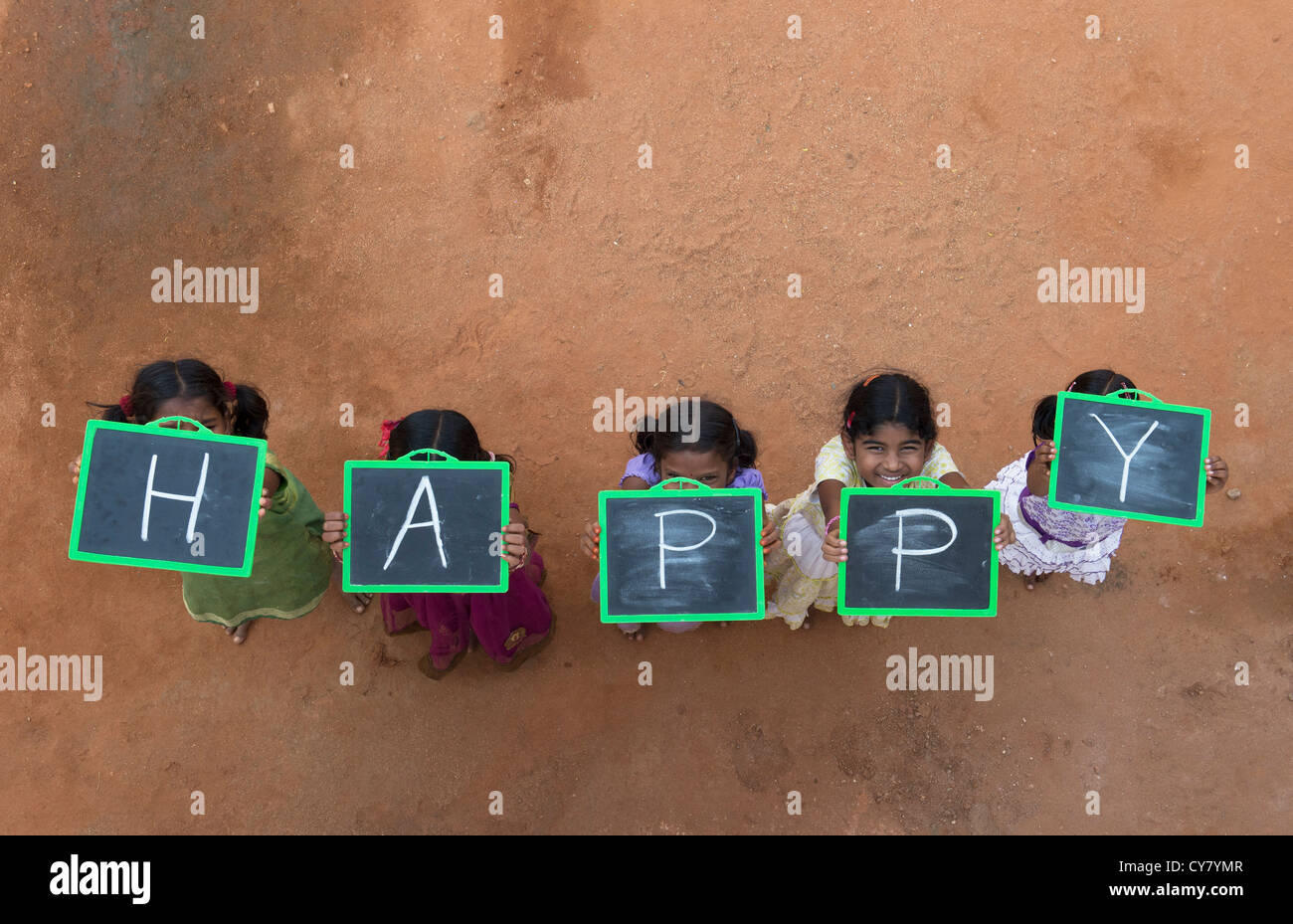 Five Indian village girls with HAPPY written on a chalkboard in a rural indian village. Andhra Pradesh, India Stock Photo