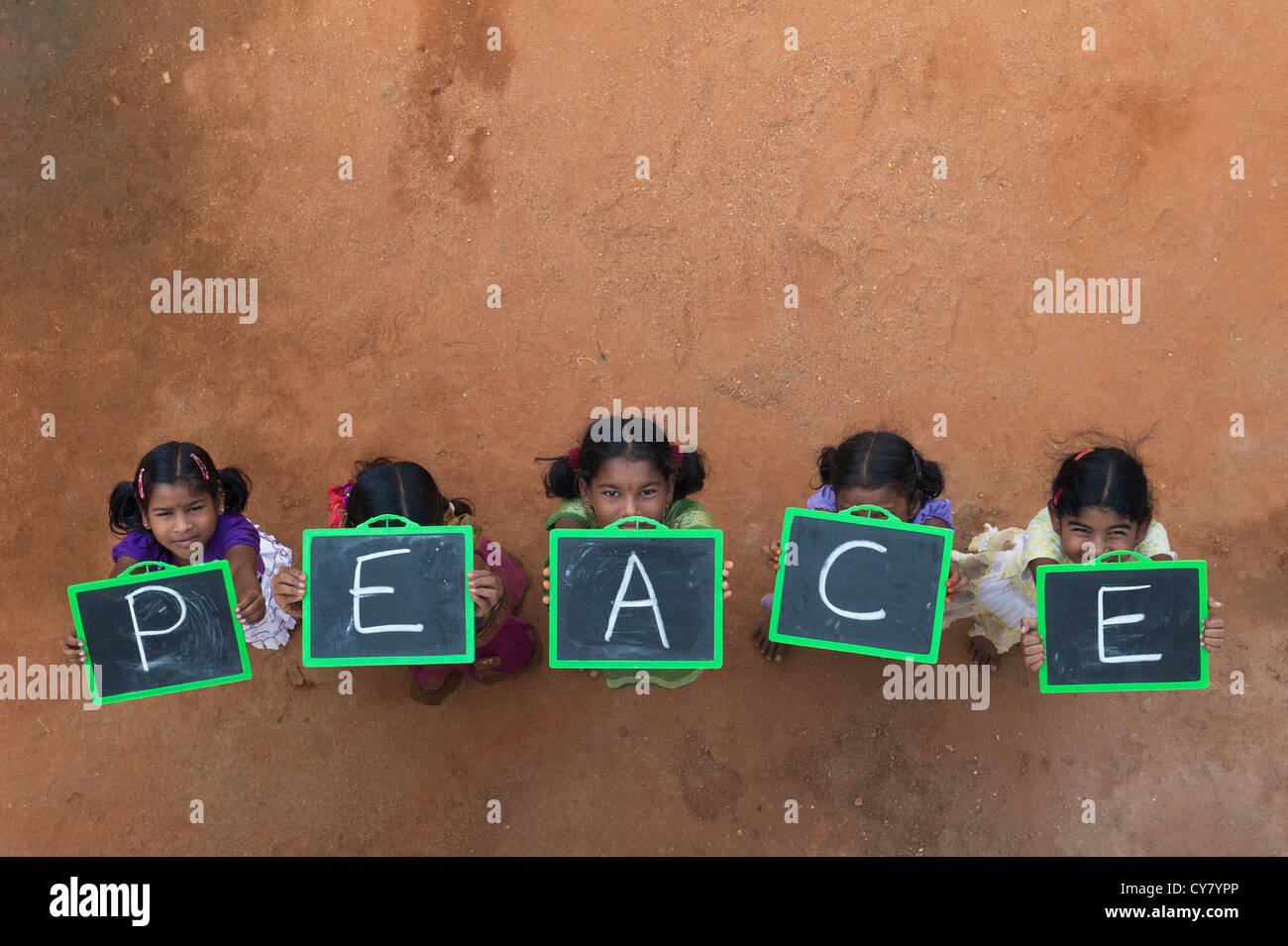 Five Indian village girls with PEACE written on a chalkboard in a rural indian village. Andhra Pradesh, India. Copy space Stock Photo