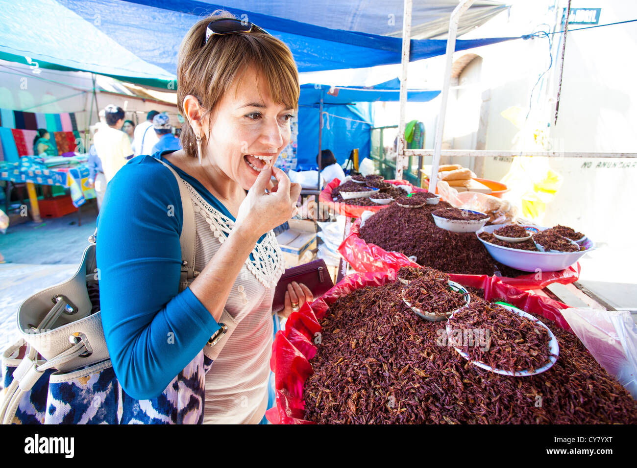 Woman tourist tries a dried grasshopper in the Tlacolula, Oaxaca market in Mexico. Stock Photo