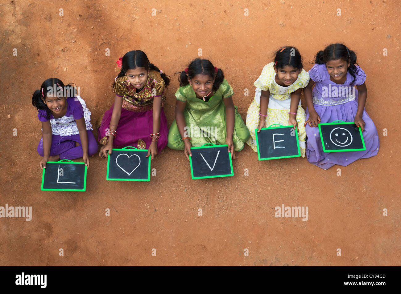 Five Indian village girls with LOVE and a smiley face written on a chalkboard in a rural indian village. Andhra Pradesh, India Stock Photo