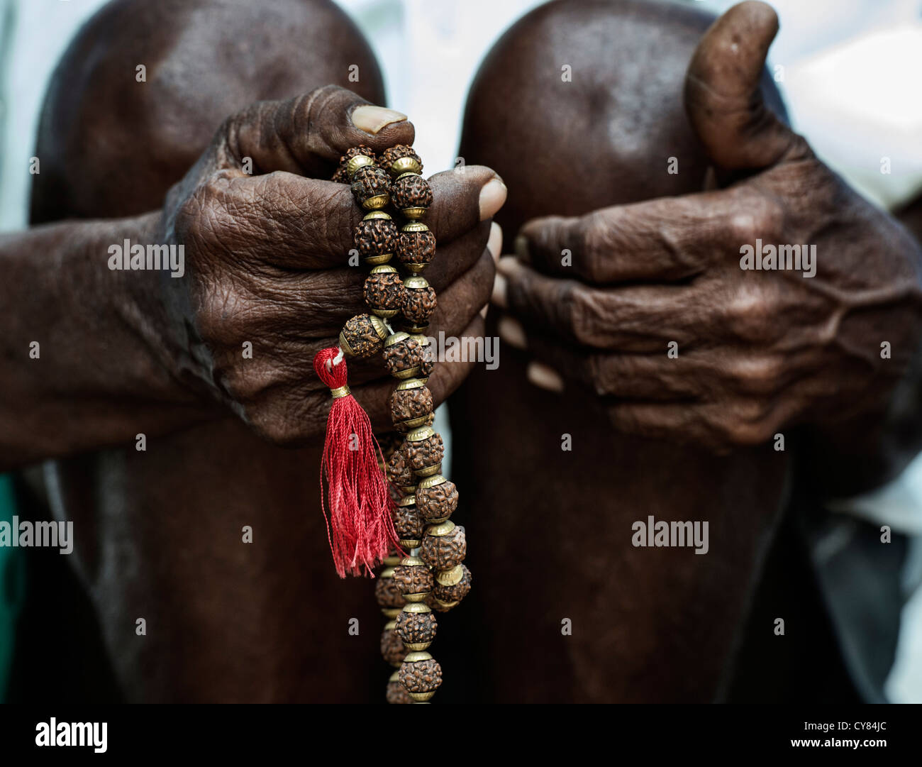 Old Indian mans hand holding Indian Rudraksha / Japa Mala prayer beads Stock Photo