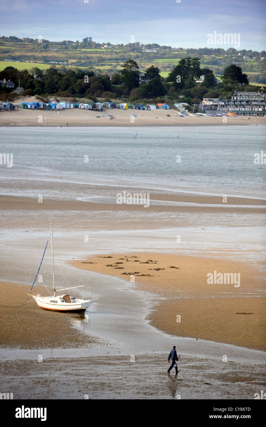A fisherman carrying a spade to dig for lugworms crosses the sands on Borth Fawr or Main Beach at Abersoch on the Lleyn Peninsul Stock Photo