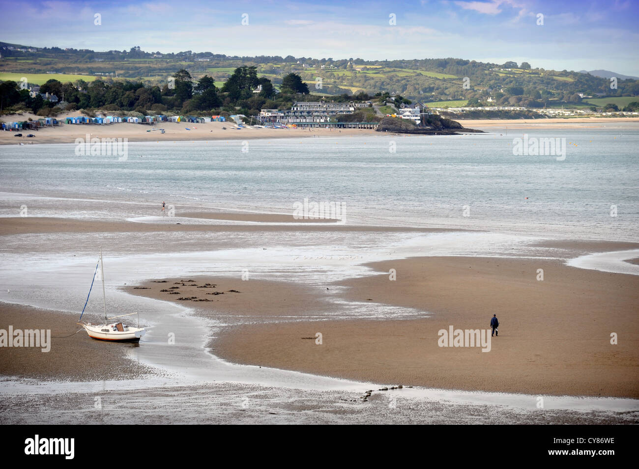 A fisherman carrying a spade to dig for lugworms crosses the sands on Borth Fawr or Main Beach at Abersoch on the Lleyn Peninsul Stock Photo