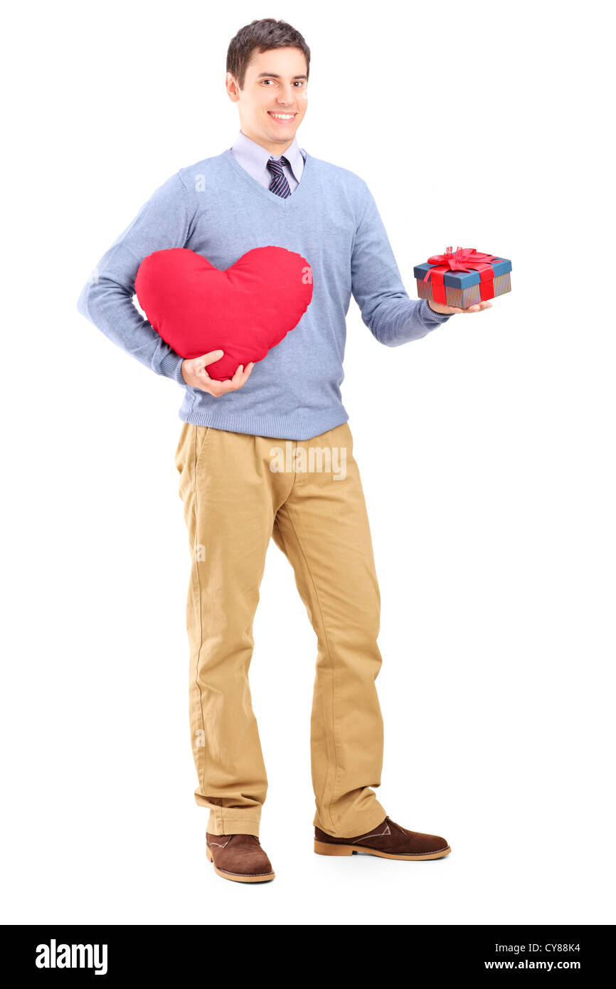 Full length portrait of a guy holding a gift and heart shape object isolated on white background Stock Photo