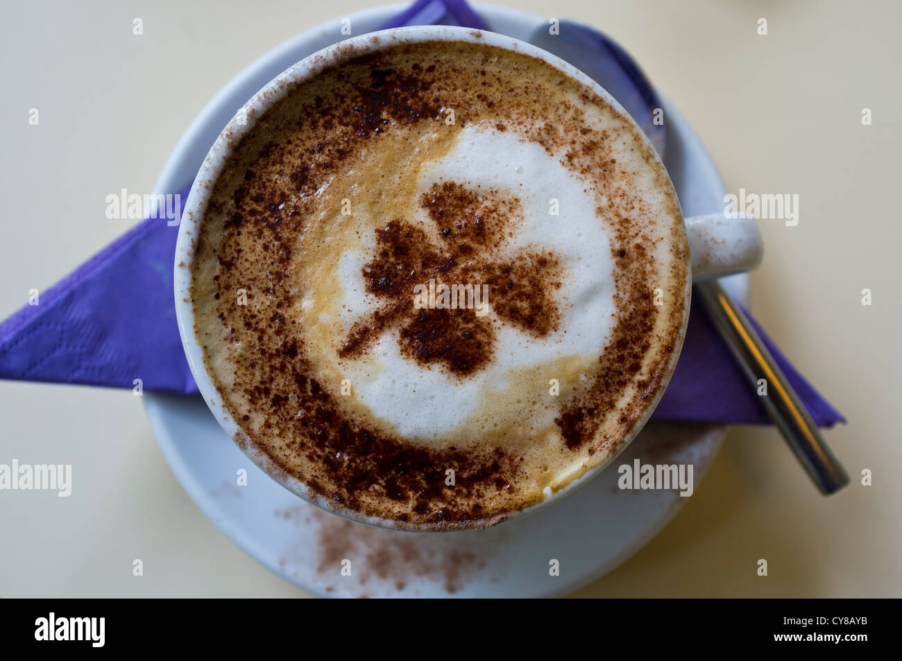 Overhead view of a cappucino coffee with a 4 leaf clover in chocolate on top Stock Photo