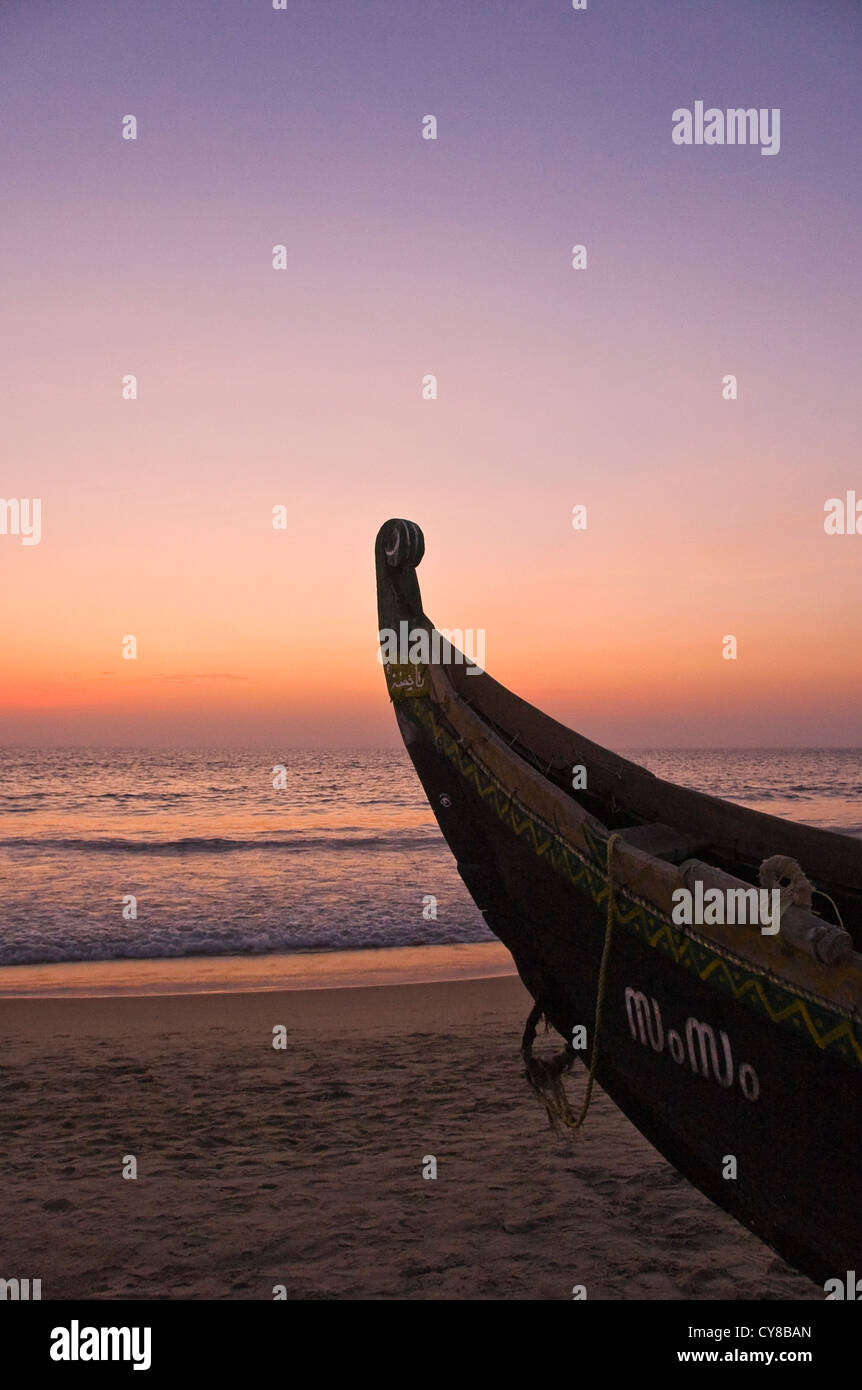 Vertical view of the bow of a fishing long boat on the beach at sunset in Kovalam. Stock Photo