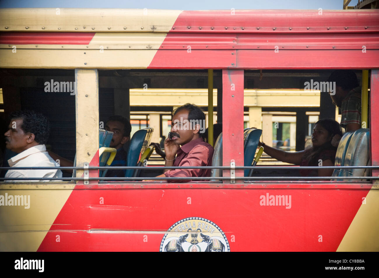 Horizontal view of a busy local bus with a passenger talking on his mobile phone. Stock Photo