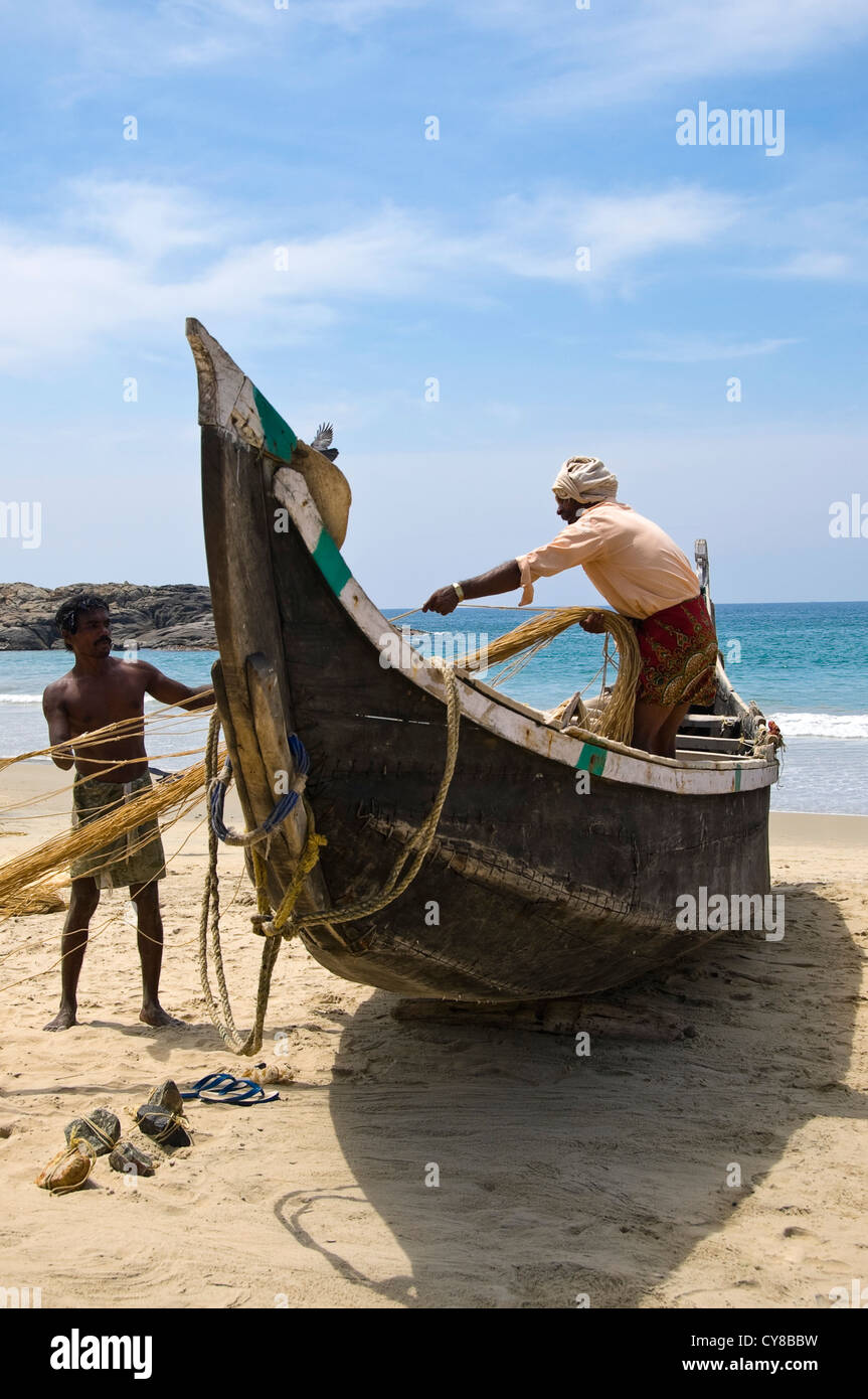 Vertical portrait of fishermen hauling nets onto a boat on ...