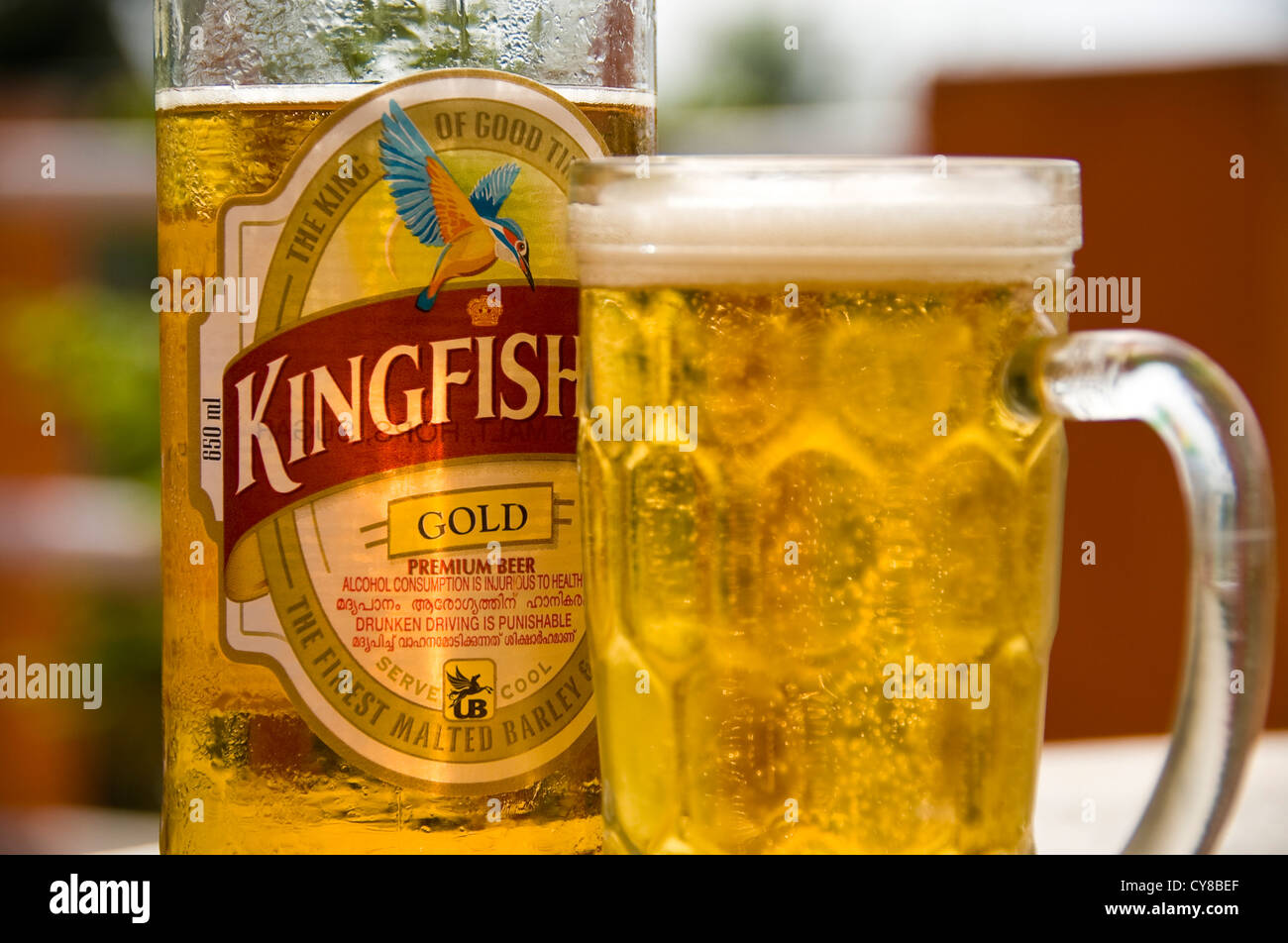Horizontal close up of a cool bottle of Kingfisher beer and a full glass on a table in India. Stock Photo