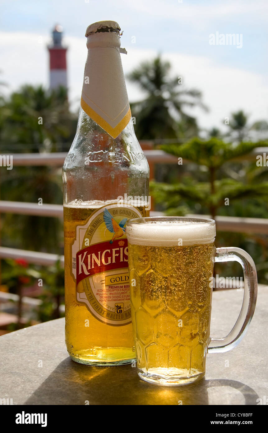 Vertical close up of a cool bottle of Kingfisher beer and a full glass on a table in Kovalam, India. Stock Photo