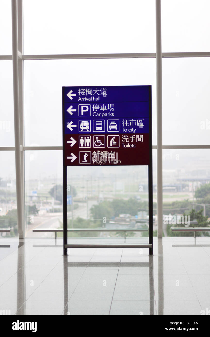 Direction sign to toilets, prayer room, transport, car parks and arrival hall.  At the Hong Kong International Airport. Stock Photo