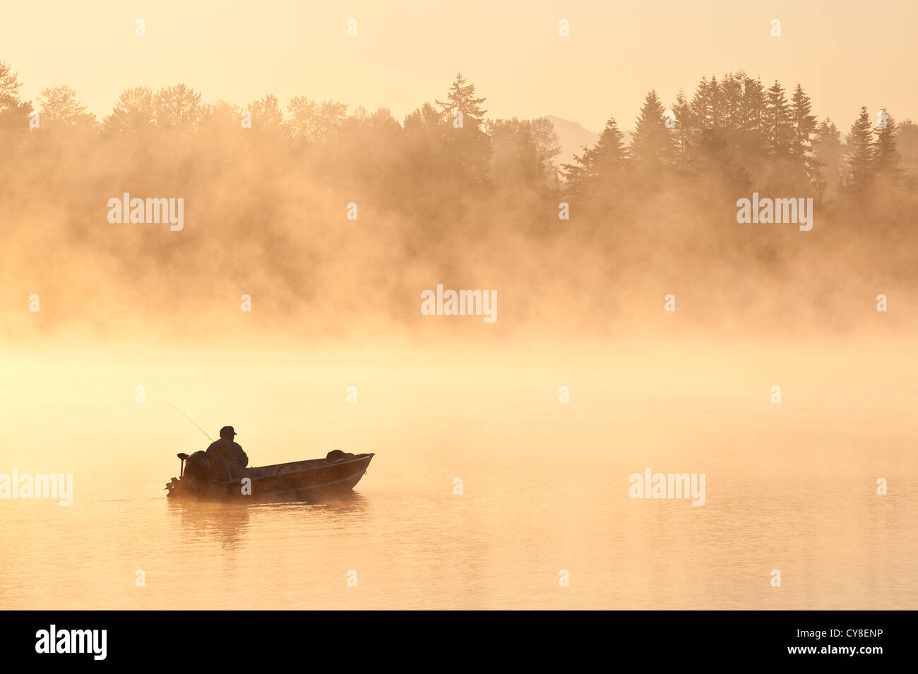 Sunrise in fog Lake Cassidy with fisherman in small fishing boat Stock