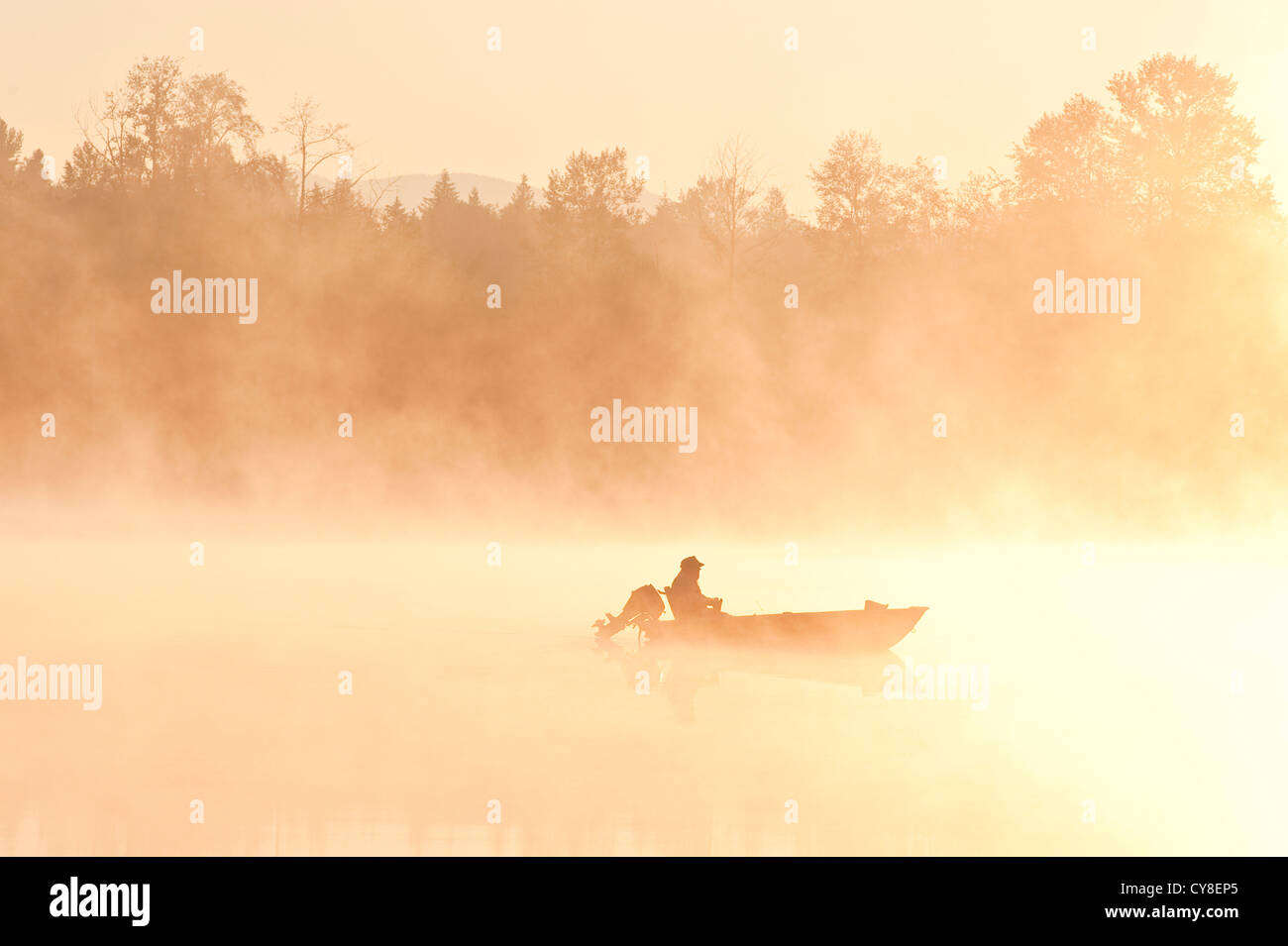 Sunrise in fog Lake Cassidy with fishermen in small fishing boat Stock