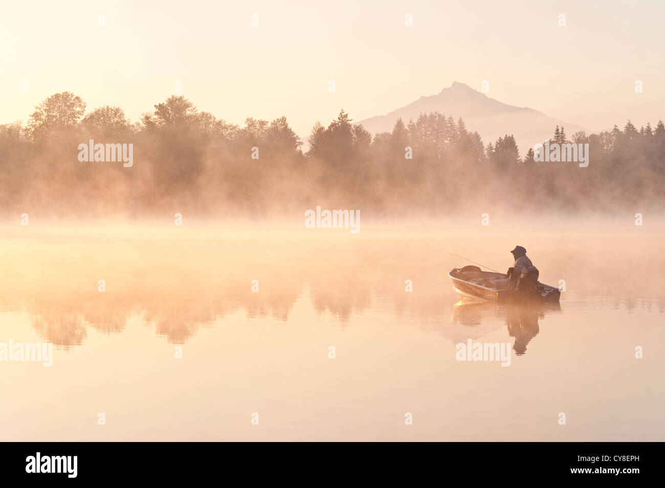 Sunrise in fog Lake Cassidy with fishermen in small fishing boat with