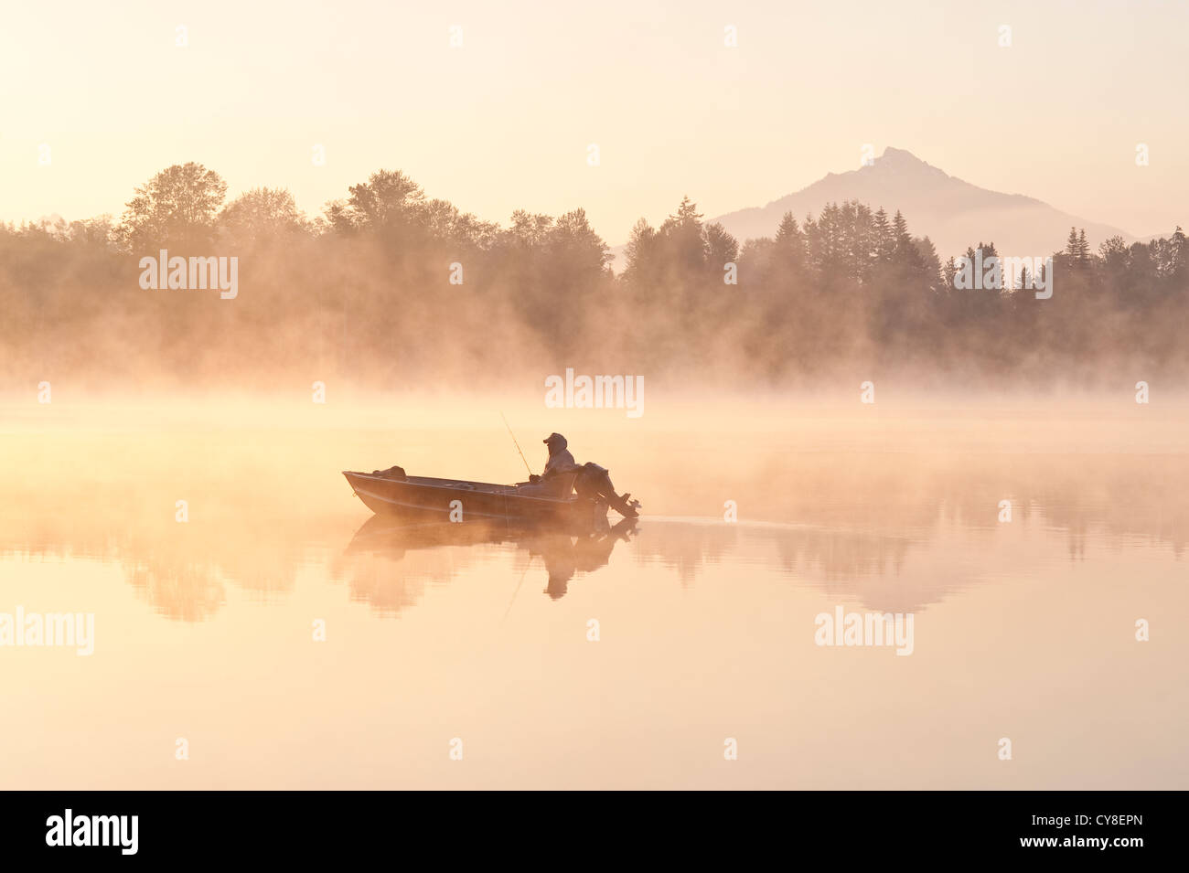 Sunrise in fog Lake Cassidy with fishermen in small fishing boat with