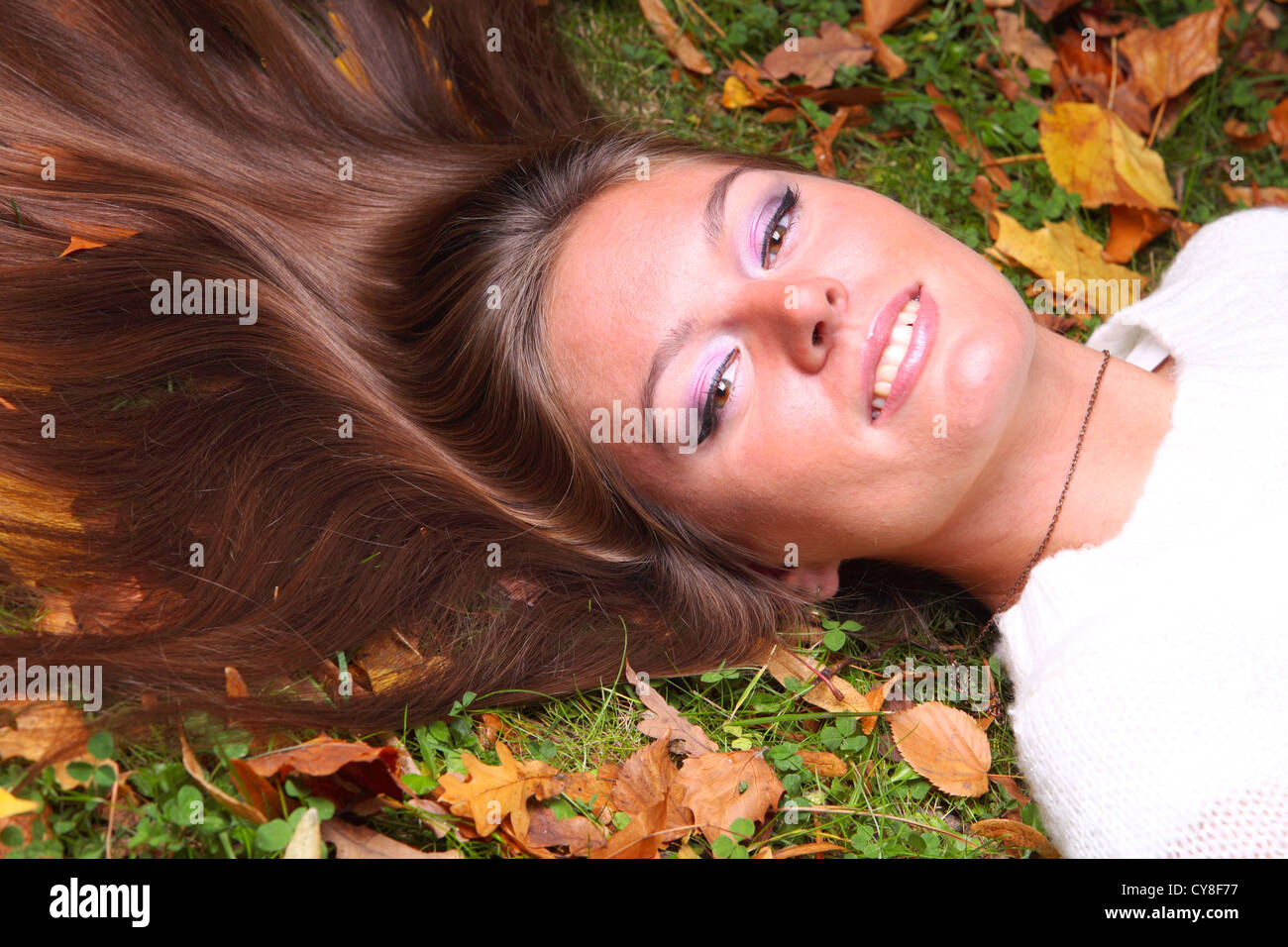 Young woman with autumn leaves in hand and fall yellow maple garden ...