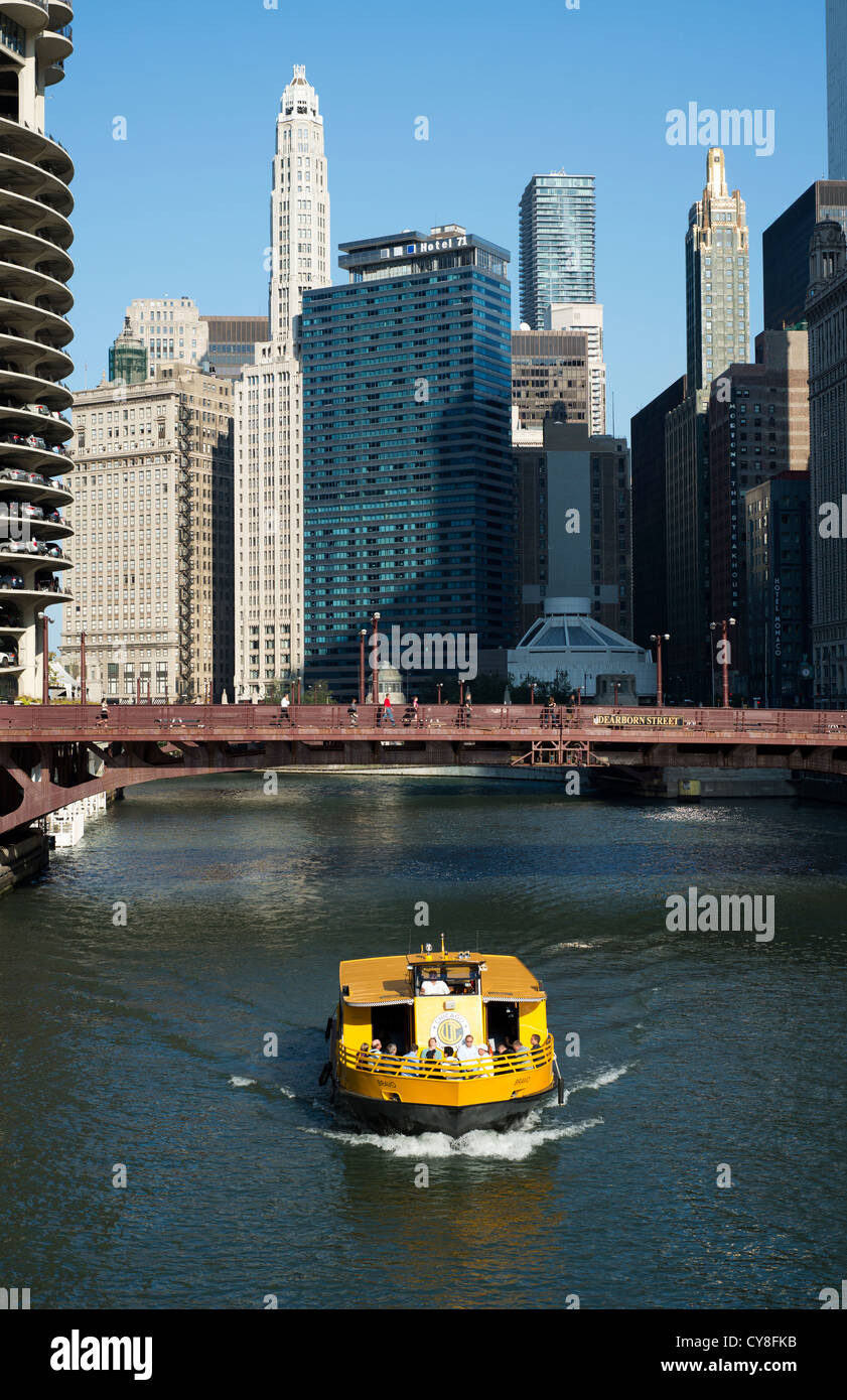A yellow Chicago water taxi travels along the Chicago River with the city skyline in the background. Stock Photo