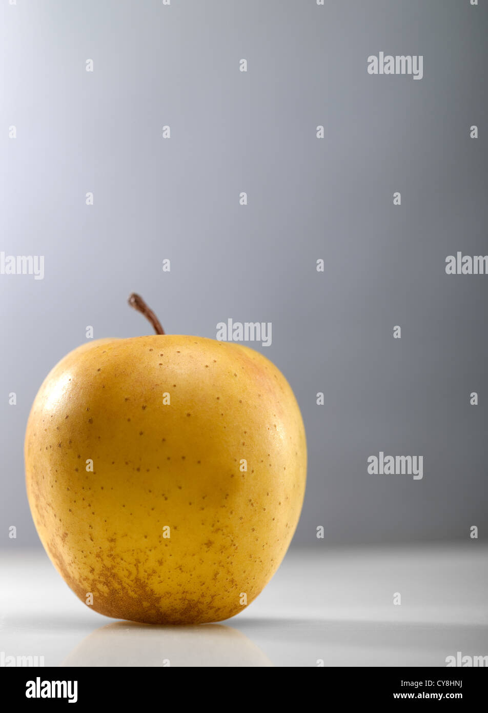 Golden apple over abstract gray backgrounds Stock Photo