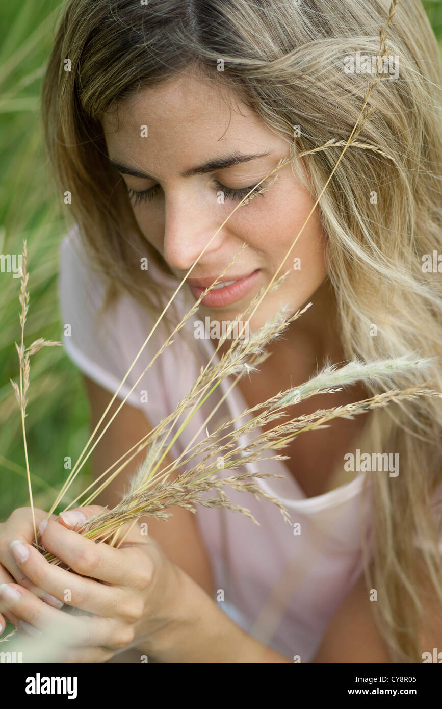 Young woman holding grass with eyes closed Stock Photo - Alamy