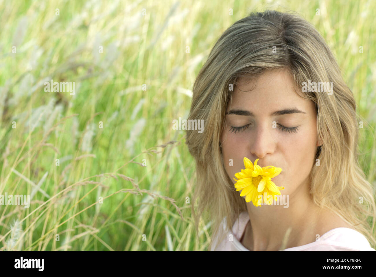 Young woman holding daisy in mouth with eyes closed Stock Photo - Alamy