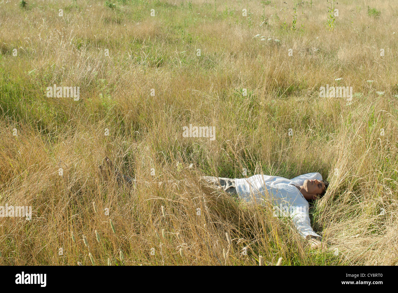 Mid-adult man relaxing in field with eyes closed Stock Photo