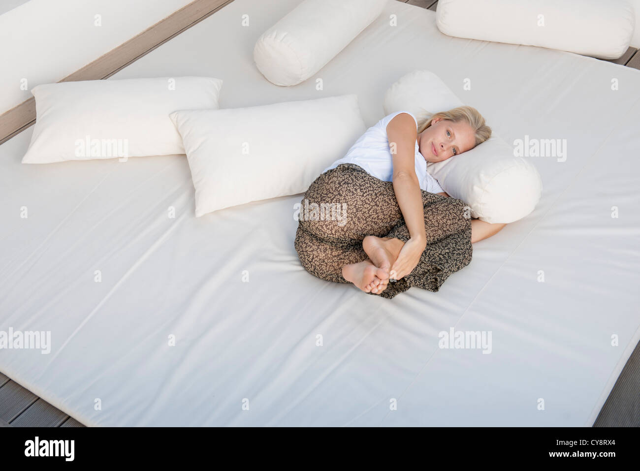 Young woman relaxing on bed in fetal position Stock Photo