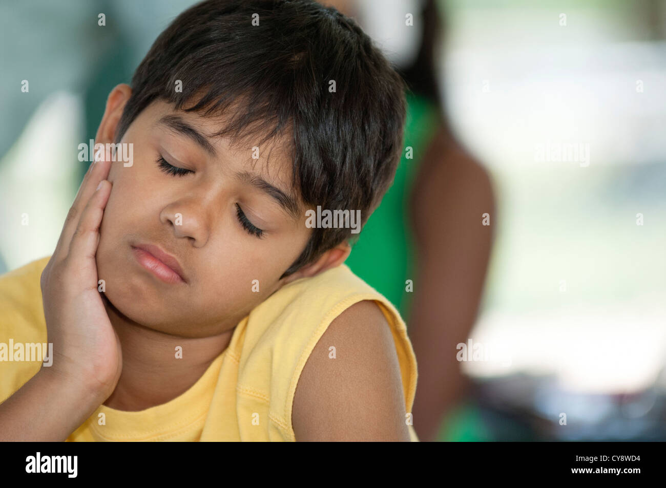 Boy resting head on chin, eyes closed Stock Photo