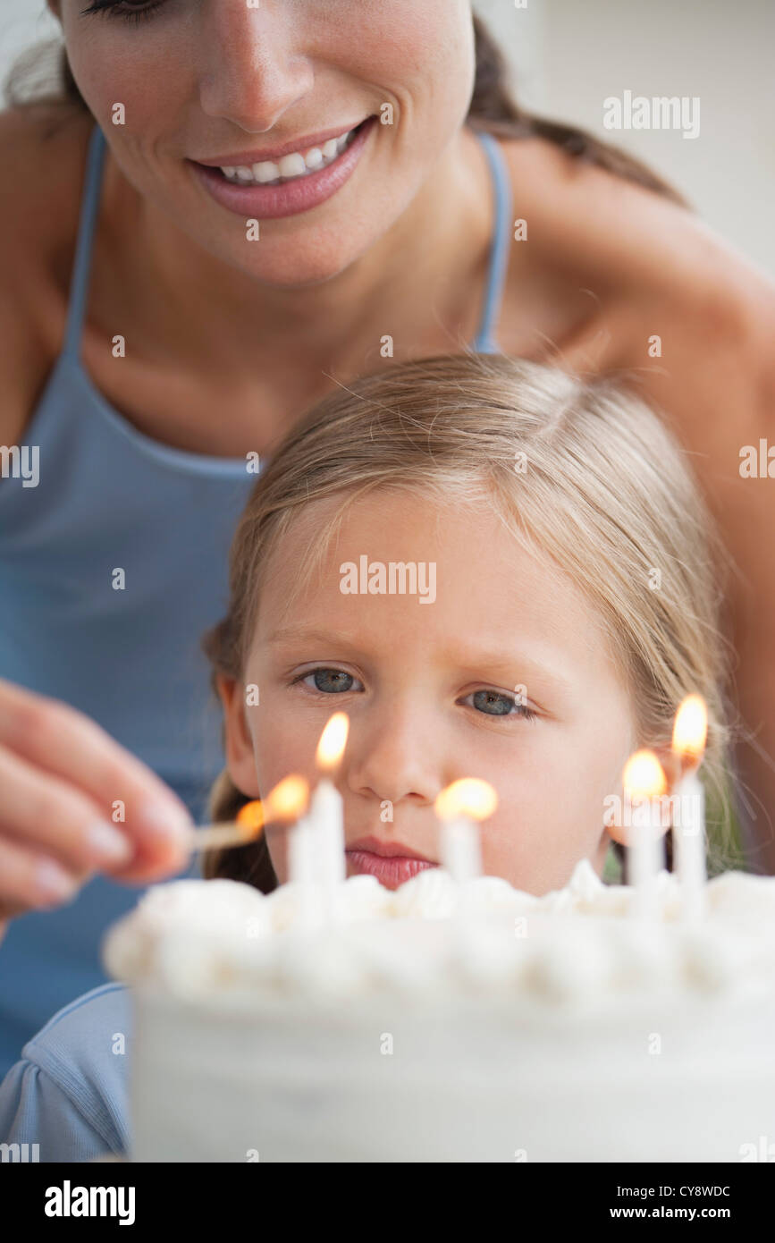 Mother lighting candles on birthday cake for girl Stock Photo