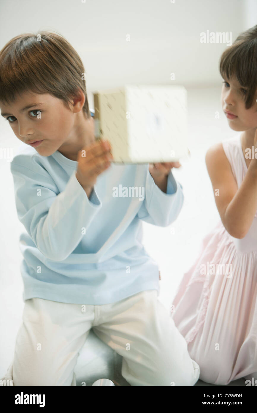 Little boy shaking gift box curiously Stock Photo