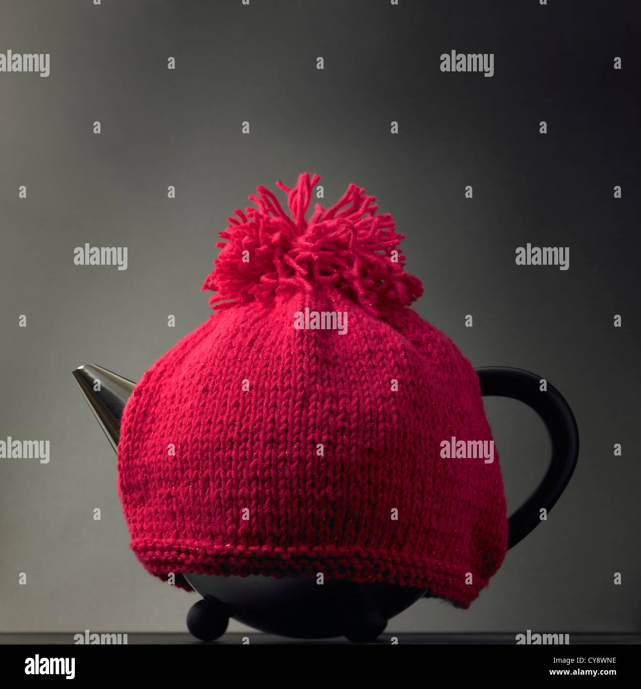 Contemporary teapot with traditional knitted red woollen tea cosy Stock Photo
