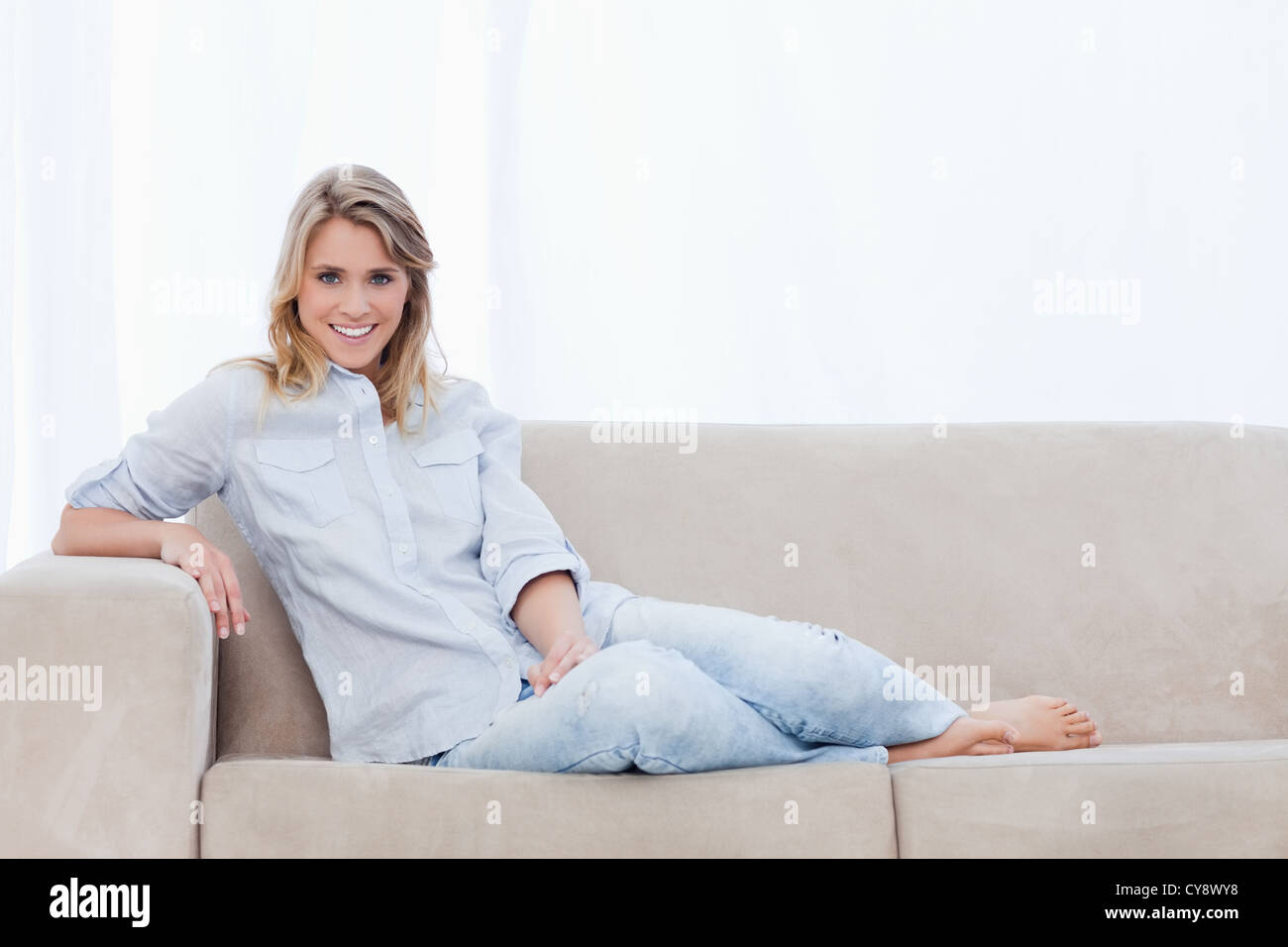 A woman smiling at the camera is sitting on a couch Stock Photo - Alamy