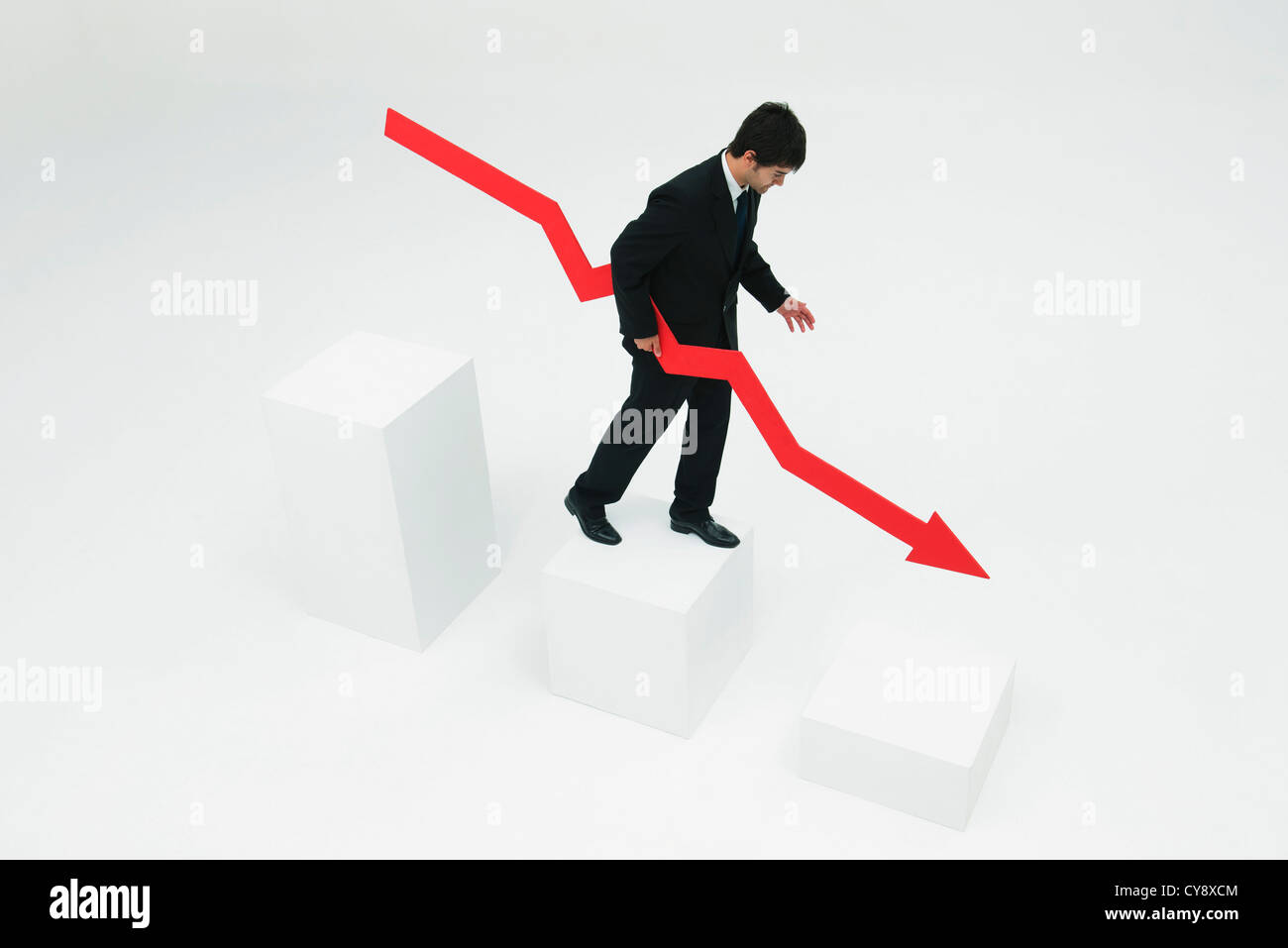 Businessman descending steps holding arrow pointed downward Stock Photo