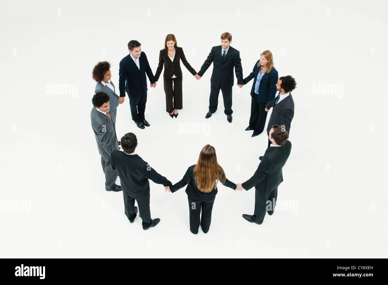 Businessmen and businesswomen standing together in circle holding hands