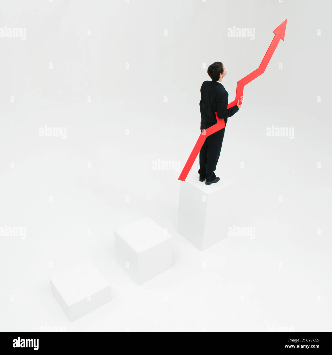 Businessman standing at top of steps holding arrow pointed upward Stock Photo