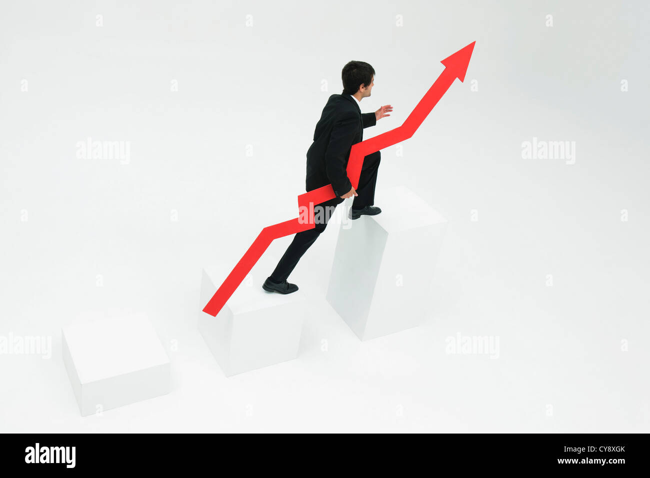 Businessman ascending steps holding arrow pointed upward Stock Photo