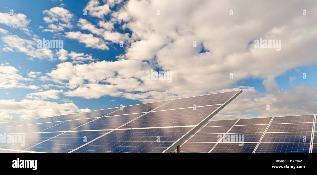 Solar photovoltaics panels field for renewable energy production with blue sky and clouds Stock Photo